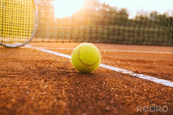 Poster  Raquette de tennis et une balle sur un court en terre battue