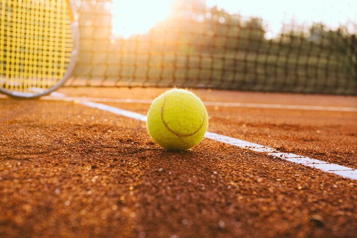 Poster  Raquette de tennis et une balle sur un court en terre battue