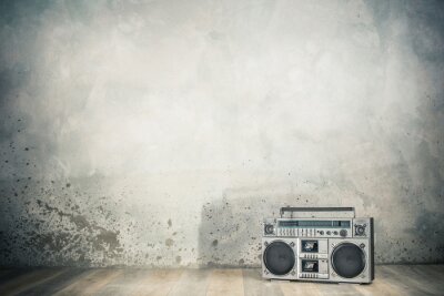 Poster  Retro outdated portable stereo boombox radio cassette recorder from 80s front concrete wall background with shadow. Vintage old style filtered photo