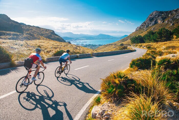 Poster  Road cycling photo. Two triathlete train in beautiful nature. Sea and mountains in background. Alcudia, Mallorca, Spain