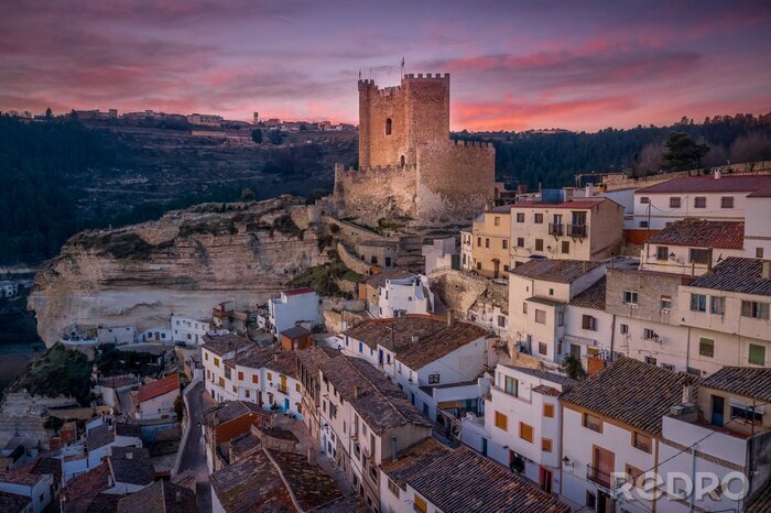 Poster  Sunset aerial panorama view of Alcala del Jucar medieval historic village with white washed houses and a castle on a rock in Albacete Spain