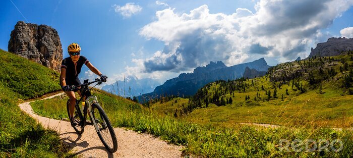 Poster  Tourist cycling in Cortina d'Ampezzo, stunning Cinque Torri and Tofana in background. Man riding MTB enduro flow trail. South Tyrol province of Italy, Dolomites.