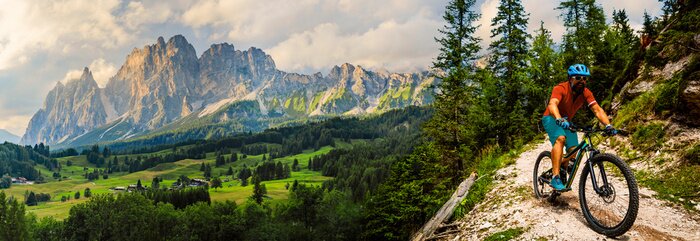Poster  Tourist cycling in Cortina d'Ampezzo, stunning rocky mountains on the background. Man riding MTB enduro flow trail. South Tyrol province of Italy, Dolomites.
