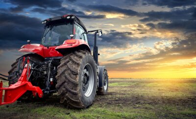Tracteur agricole travaillant dans le champ au coucher du soleil
