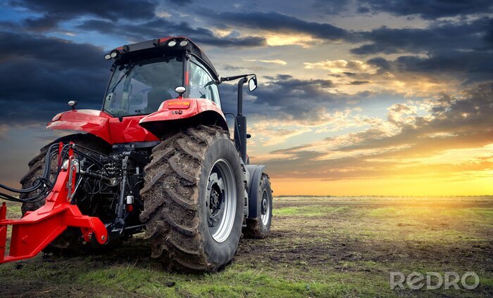 Poster  Tracteur agricole travaillant dans le champ au coucher du soleil