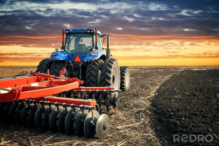 Poster  Tracteur labourant le champ sur fond de coucher de soleil