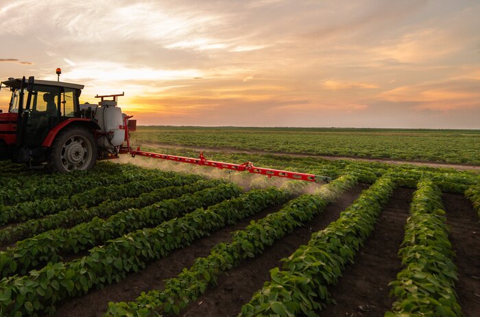 Poster  Tractor spraying soybean field in sunset