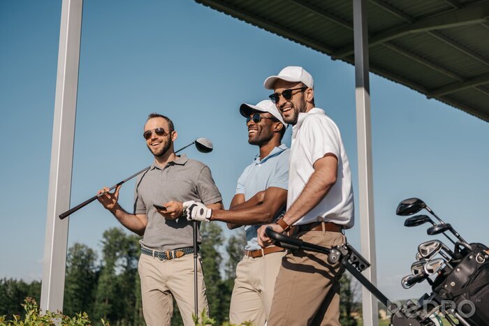 Poster  Trois hommes souriants dans des lunettes de soleil tenant des clubs de golf en plein air