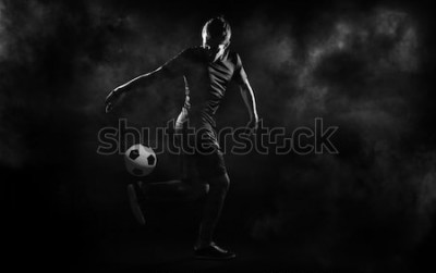 Poster  Un joueur de football jonglant sur fond noir