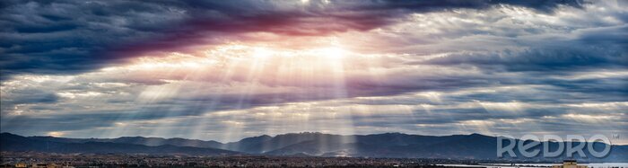 Poster  Feu de lumière à travers les nuages ​​sur les montagnes - Des rayons de lumière qui brillent à travers des nuages ​​sombres, un ciel dramatique avec un nuage