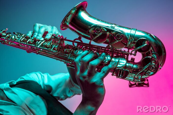 Sticker  African American handsome jazz musician playing the saxophone in the studio on a neon background. Music concept. Young joyful attractive guy improvising. Close-up retro portrait.
