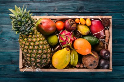 Sticker  Fruits tropicaux dans une boîte en bois. Papaye, fruit du dragon, ramboutan, tamarin, fruit de cactus, avocat, granadilla, carambole, kumquat, mangue, mangoustan, fruit de la passion, noix de coco.