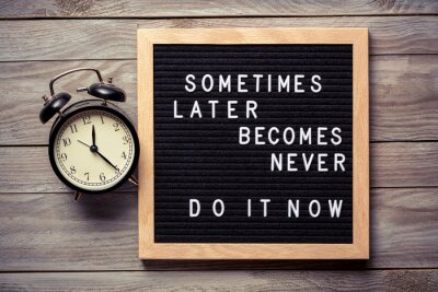 Sticker  Inspirational motivational quote Sometimes later becomes never. Do it now words on a letter board on wooden background near vintage alarm clock. Success and motivation concept.