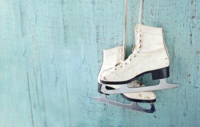 Sticker  Les patins de glace de la femme suspendue sur fond de bois bleu