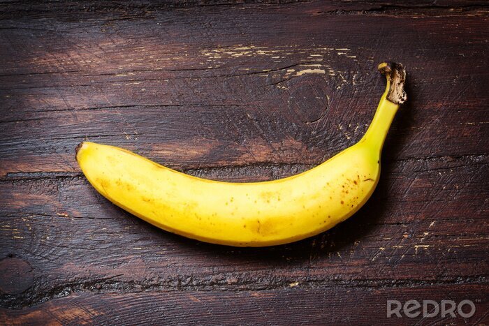 Sticker  Une banane posée sur une surface en bois sombre