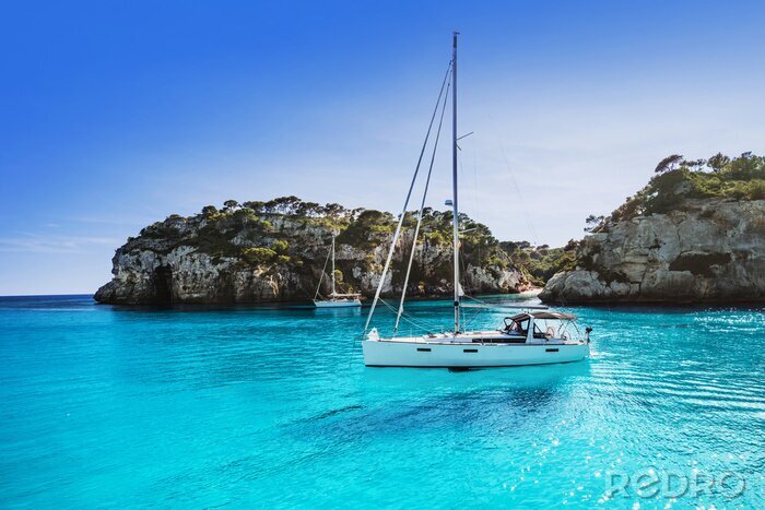Tableau  Beautiful beach with sailing boat yacht, Cala Macarelleta, Menorca island, Spain. Yachting, travel and active lifestyle concept	