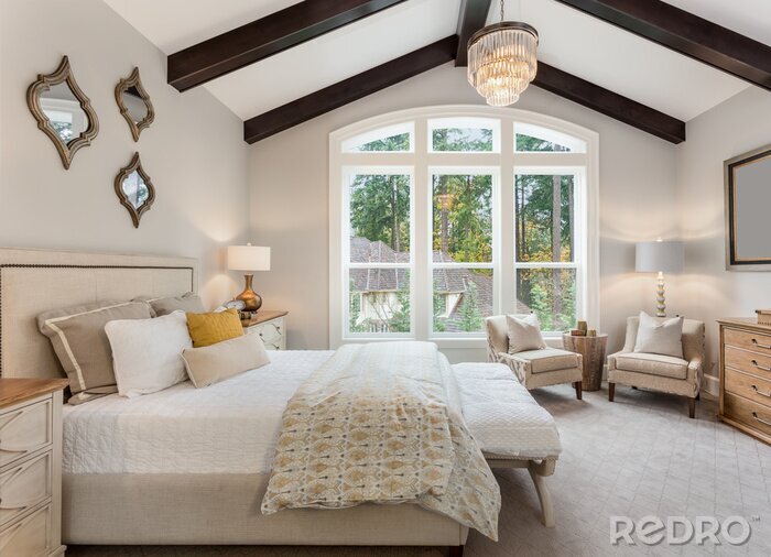 Tableau  Beautiful furnished master bedroom interior in luxury home . Features vaulted ceiling with wood beams and chandelier.
