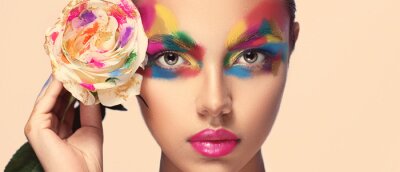 Tableau  Beautiful girl model with multi-colored paints on her face. Woman with rose flower and bright color make-up. Cosmetics, beauty and makeup.  Spring and summer flowering  shopping