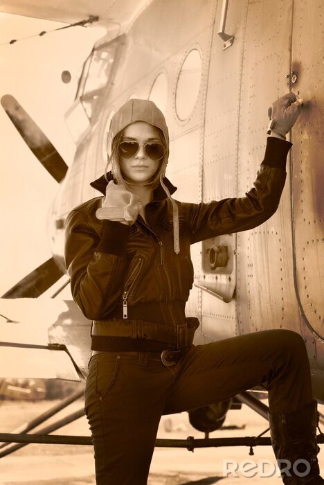 Tableau  Belle fille en veste debout à côté d'avions de guerre.