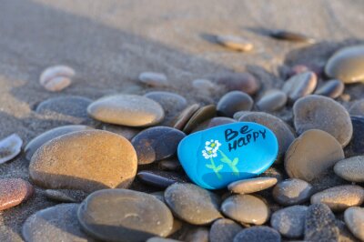 Tableau  blue stone with the inscription be happy on the beach among the stones