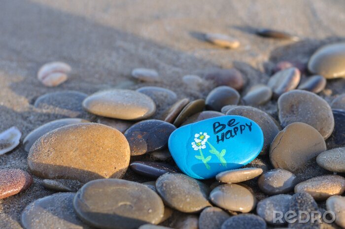 Tableau  blue stone with the inscription be happy on the beach among the stones