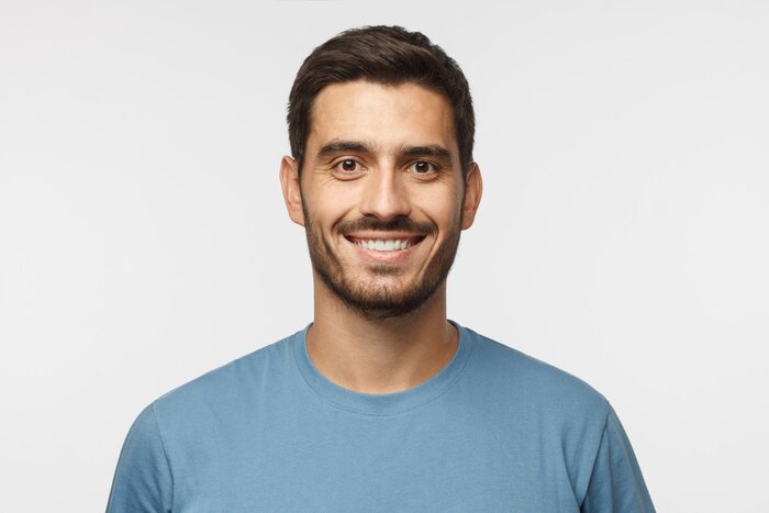 Tableau  Bouchent portrait de jeune beau mec souriant en t-shirt bleu isolé sur fond gris