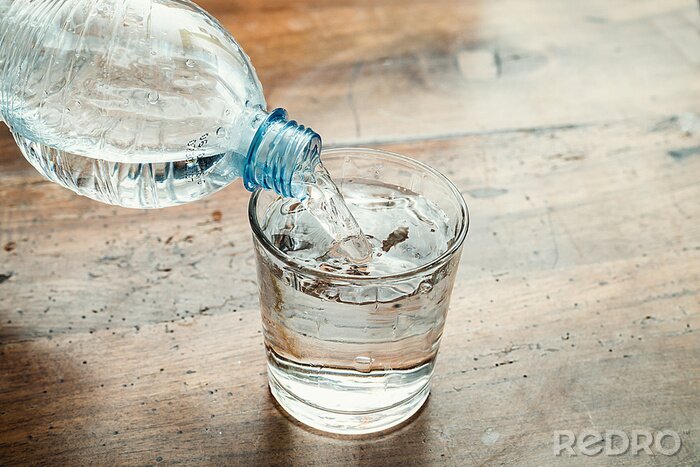 Tableau  bouteille d'eau bleue versé dans un verre clair