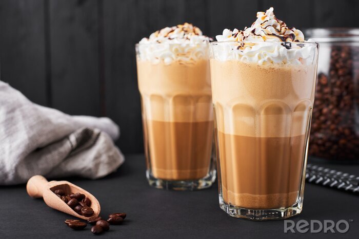 Tableau  Café au lait glacé au caramel dans un grand verre avec du sirop au chocolat et de la crème fouettée. Fond en bois foncé