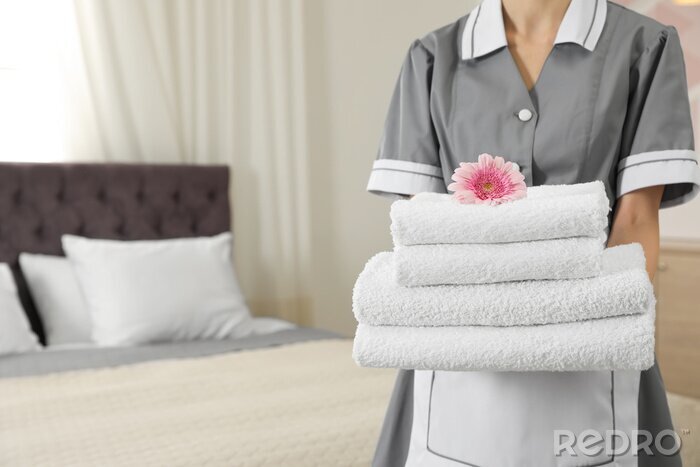 Tableau  Chambermaid with stack of fresh towels in hotel room, closeup. Space for text