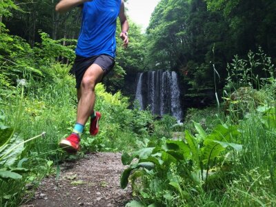 Close up of trail runner with waterfall in background