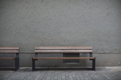Tableau  Closeup shot of wooden benches against a grey stone wall in an empty street