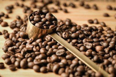 Tableau  Coffee beans are poured on a wooden surface and in the middle is a coffee spoon full of beans