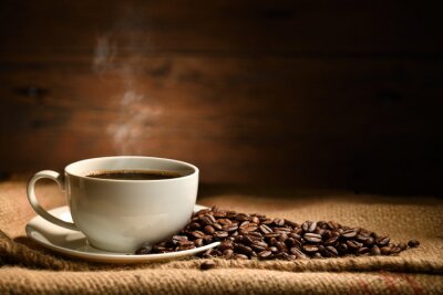 Tableau  Cup of coffee with smoke and coffee beans on burlap sack on old wooden background