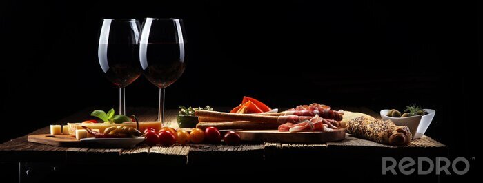 Tableau  Ensemble de collations au vin d’antipasti italien. Variété de fromage, olives méditerranéennes, crudo, prosciutto di Parma, salami et vin dans des verres sur fond grunge en bois.