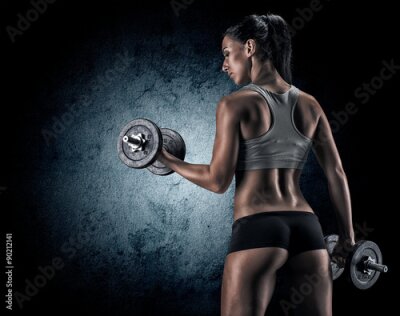 Femme musclée en studio sur fond sombre