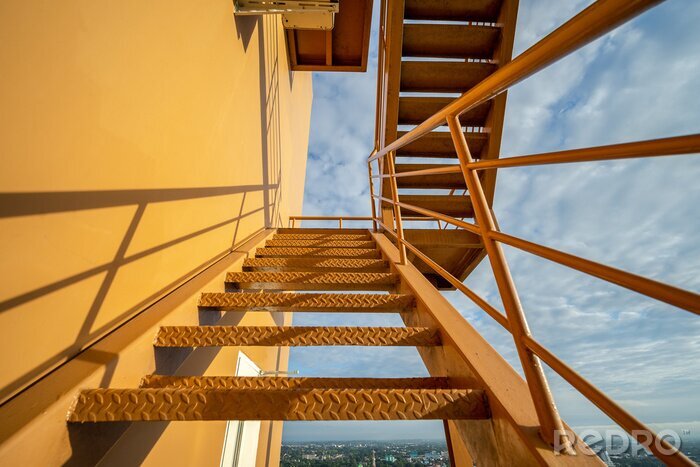Tableau  Fire escape stairs mounted to the outside, Emergency exit with yellow wall..