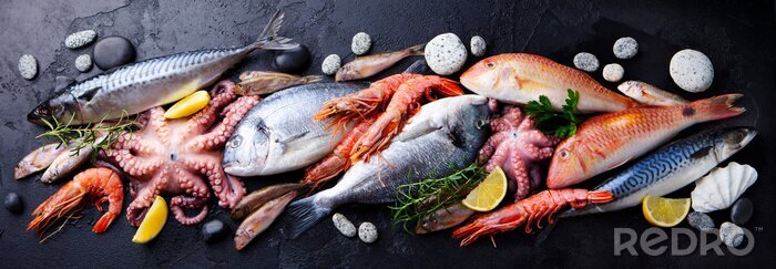 Tableau  Fresh fish and seafood assortment on black slate background. Top view.