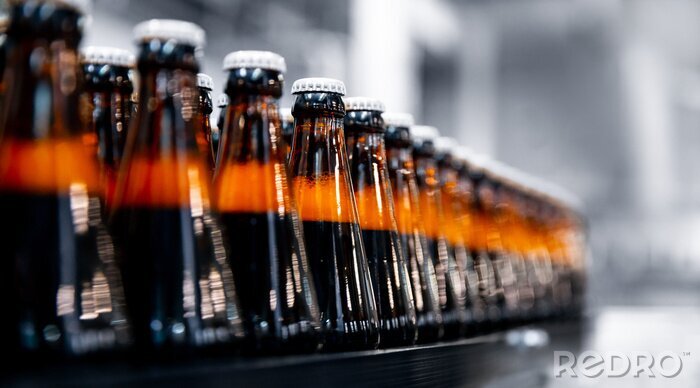 Tableau  Glass bottles of beer on dark background with sun light. Concept brewery plant production line