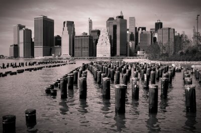 Horizon de Manhattan avec poteaux en bois dans l'eau, noir et blanc