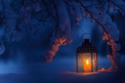 Lanterne à bougie sous les branches enneigées au crépuscule. Noël dans un jardin hivernal.