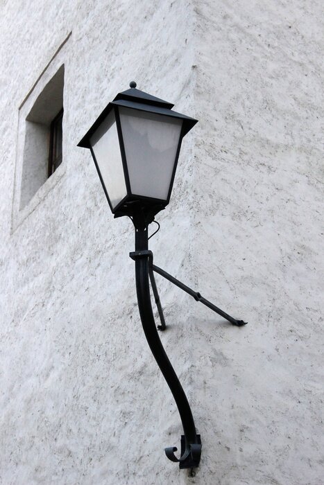 Tableau  Lanterne de rue avec abat-jour en verre et support en fonte sur le mur du vieux bâtiment. Fragment abstrait de l'architecture médiévale.