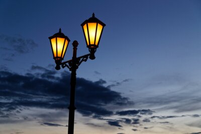 Lanterne de rue vintage avec une lumière jaune chaude et un ciel nuageux nuit bleu foncé sur fond