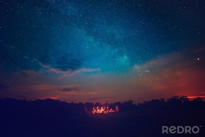 Tableau  Le feu de camping sous le ciel étoilé bleu étonnant avec beaucoup d'étoiles brillantes et de nuages. Voyage, récréatif, activité, concept.