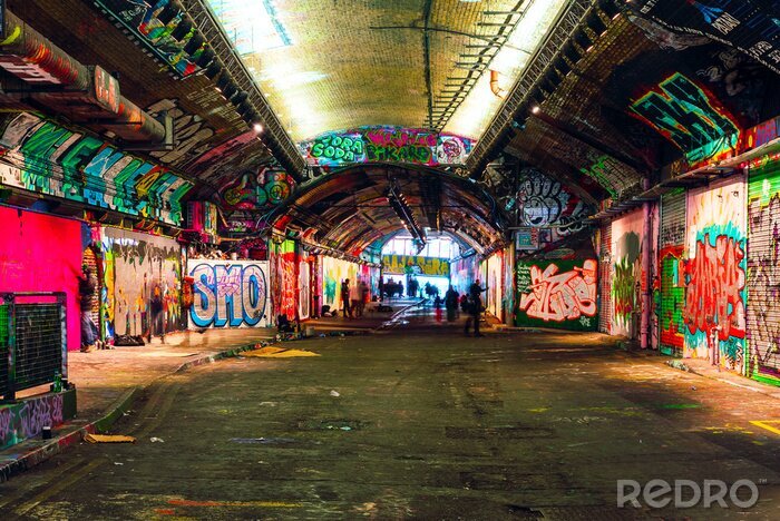 Tableau  London, UK/Europe; 21/12/2019: Leake Street, underground tunnel with graffiti covered walls in London. Scene with pedestrians and graffiti artists.