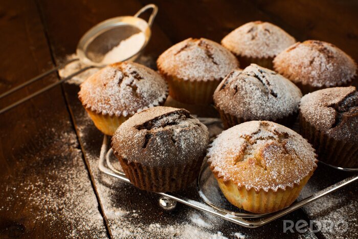 Tableau  Muffins à la vanille et au chocolat, sucre en poudre, tamis pour une cuisson sur fond de bois sombre, sélective