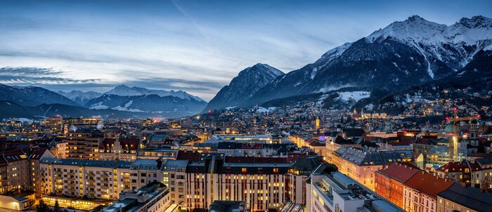 Tableau  Panorama der Skyline von Innsbruck, Alpen, Österreich, im Winter am Abend mit schneebedeckten Bergen im Hintergrund