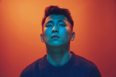 Tableau  Portrait of a guy with colorful neon light on gradient studio background. Male model with calm and serious mood. Facial expression, cyberpunk, millenials lifestyle and look like. Future, technologies.