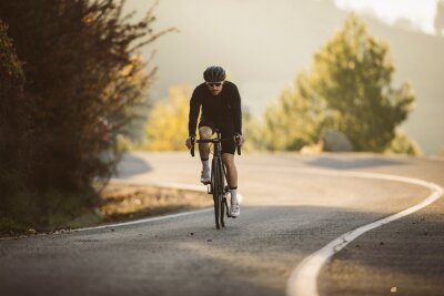 Tableau  Professional road bicycle racer in action. Men cycling mountain road bike at sunset.