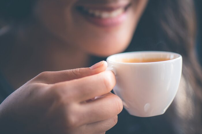 Tableau  Smiling woman holing hot espresso coffee on hand at cafe in the morning