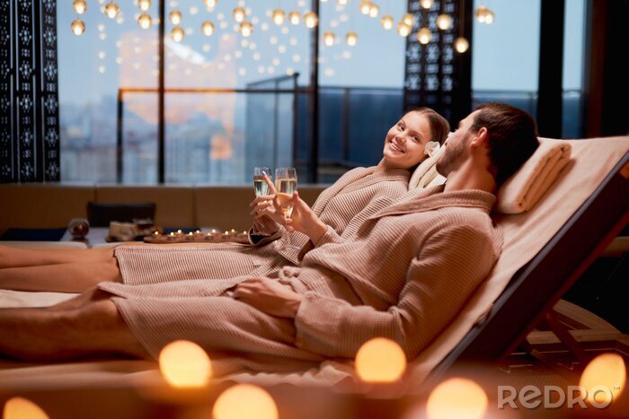 Tableau  Spa, relax, enjoying concept. Married couple together relaxing in spa salon, lying on beds drinking champagne, using candles